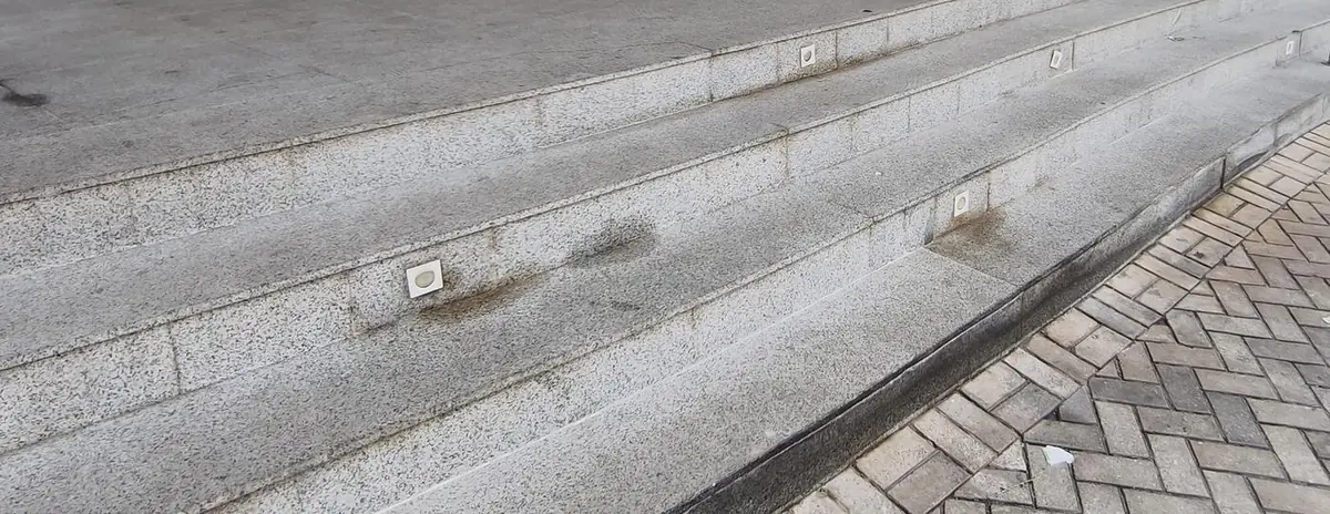 Degraus de granito manchados, com marcas escuras em volta das luminárias embutidas