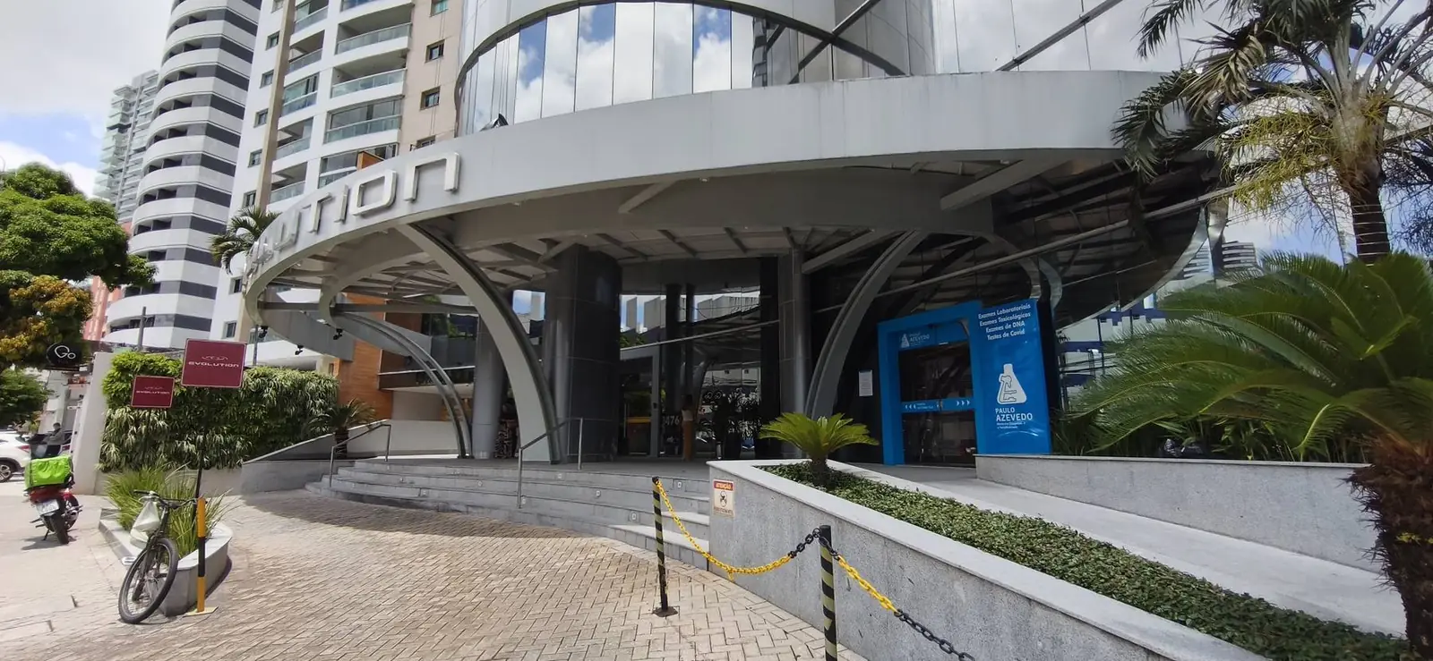 Fachada do Edifício Evolution com o pátio de acesso coberto, escadaria em curva e floreiras